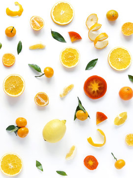Creative flat layout of fruit, top view. Sliced orange, lemon, persimmon, tangerine, green leaves isolated on white background. Food wallpaper, composition pattern of fresh fruits.	