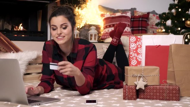 Cheerful woman using credit card during christmas online shopping
