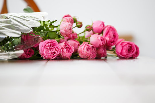 Photo of bouquet of pink peonies on white wooden table
