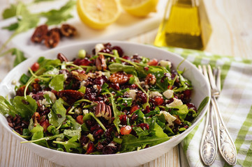 Salad with wild rice, arugula,  pomegranate, pecan nuts, cranberries and feta cheese.