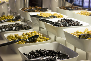 Selection of black and green olives in white bowls