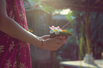 Woman holding canang sari - offering for Gods. Balinese tradition.