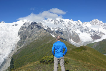tourist stands on the background of a mountainous landscape.