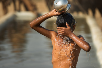 Bath in the desert.A child taking bath in watering trough or puddle in the desert, India. Water concept