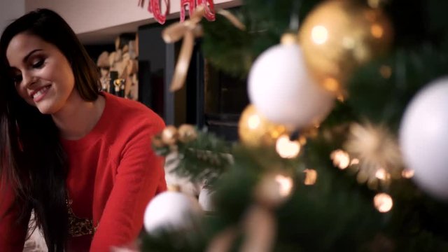 Cheerful woman unpacking gift box at christmas tree