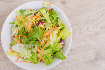 Salad and fresh vegetables on wooden table background