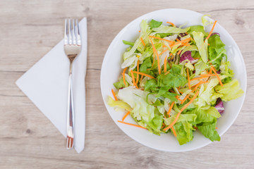Salad and fresh vegetables on wooden table background