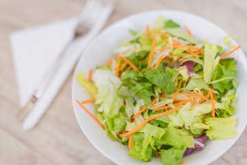 Salad and fresh vegetables on wooden table background