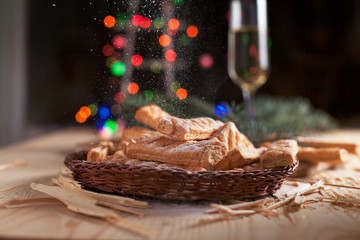 homemade cookies, glasses with champagne and a New Year tree on a festive table on a background of multi-colored New Year's lights