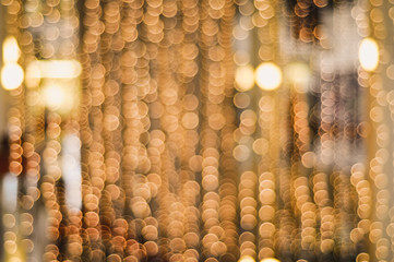 Golden blurry Christmas chain lights creating a beautiful bokeh effect hanging in a window in New York City in front of a dark background