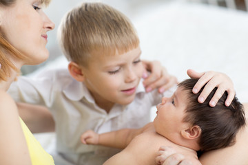 Closeup of happy family. Joyful mom and her child son looking at newborn baby.