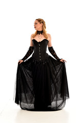 Fototapeta premium full length portrait of a blonde girl wearing black gothic gown. standing pose, isolated on white background.