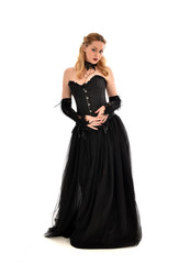 Fototapeta premium full length portrait of a blonde girl wearing black gothic gown. standing pose, isolated on white background.