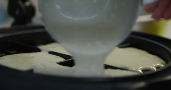 Waffle batter being poured into waffle maker steaming - close up