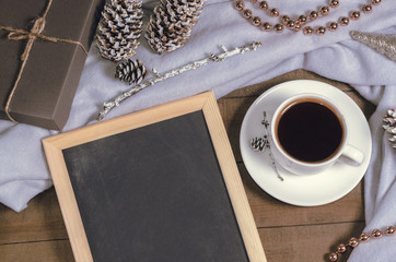 A cup of black coffee in Christmas decor and a slate with free space for text top view