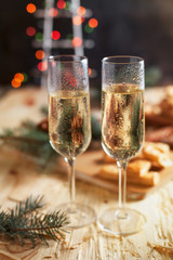 glasses with champagne, biscuits, a Christmas tree and New Year's lights on a New Year's festive table