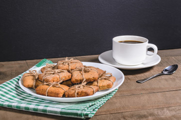 Black coffee in a white cup on a green napkin and homemade cookies.