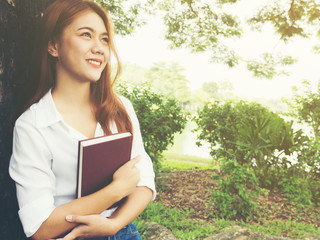 Fototapeta premium Young woman stand holding book at the park.