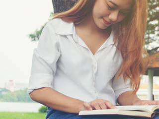 Obraz premium Young woman sitting reading book at the park.