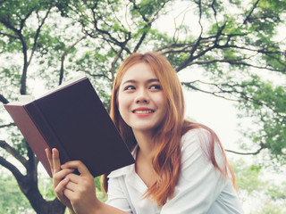 Fototapeta premium Young woman sitting reading book at the park.