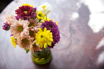 Colorful flowers in a vase on a wooden table.