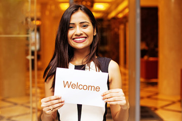 Hotel manager holding a welcome sign in front of the hotel entrance