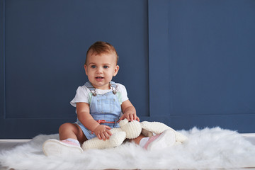 Cute blue-eyed baby girl with toy sitting on the floor