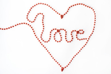 The word LOVE and symbol heart- declaration of written with red beads isolated on white background