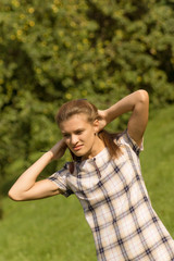 Portrait of a young beautiful woman adjusting her hair on a sunny day. Cute girl straightens her hair in the bright sun