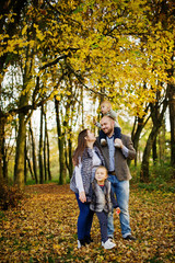 Happy caucasian family of mom dad and little girl with boy at majestic autumn fall forest.