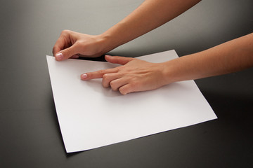 Fototapeta premium Female hands with paper on a black background. Studio