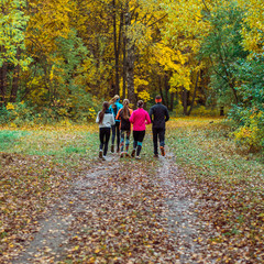Fototapeta premium Running athletes in the park on a run in the early morning. Several children are running in the woods doing sports. Healthy lifestyle.