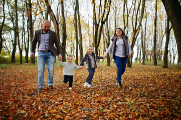 Naklejka premium Happy caucasian family of mom dad and little girl with boy at majestic autumn fall forest.
