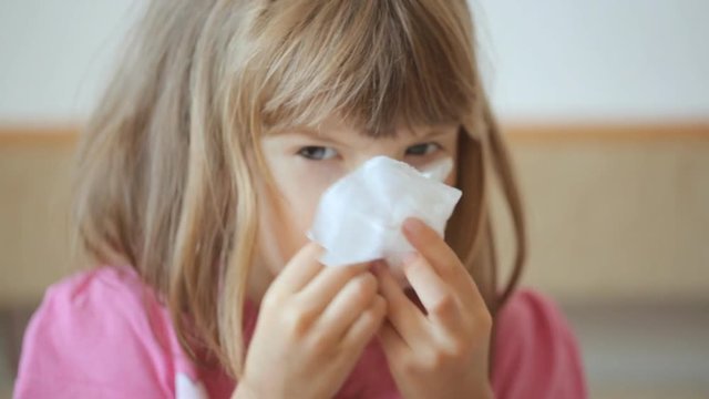 Little girl blowing her nose