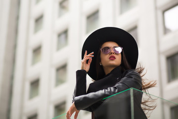 Fashion portrait of pretty woman in wide brimmed black hat and mirror sunglasses