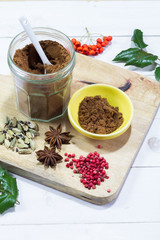 Gingerbread spices in the jar. White, wooden table. Wooden kitchen board.