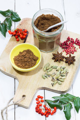 Gingerbread spices in the jar. White, wooden table. Wooden kitchen board.
