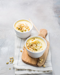 Classic cheesecake in small ceramic jars with nuts and honey on light concrete background and wooden board. The most delicious dessert or the perfect healthy breakfast!)