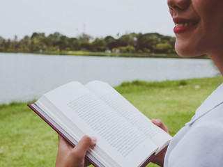 Close up young woman reading book at the park.