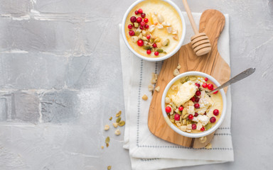 Classic cheesecake in small ceramic jars with fresh cranberries, nuts and honey on light concrete background and wooden board. The most delicious dessert or the perfect healthy breakfast!)