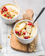 Classic cheesecake in small ceramic jars with fresh cranberries, nuts and honey on light concrete background and wooden board. The most delicious dessert or the perfect healthy breakfast!)