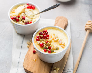 Classic cheesecake in small ceramic jars with fresh cranberries, nuts and honey on light concrete background and wooden board. The most delicious dessert or the perfect healthy breakfast!)