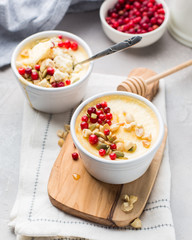 Classic cheesecake in small ceramic jars with fresh cranberries, nuts and honey on light concrete background and wooden board. The most delicious dessert or the perfect healthy breakfast!)