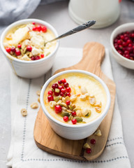 Classic cheesecake in small ceramic jars with fresh cranberries, nuts and honey on light concrete background and wooden board. The most delicious dessert or the perfect healthy breakfast!)