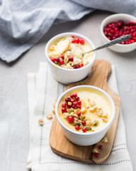 Classic cheesecake in small ceramic jars with fresh cranberries, nuts and honey on light concrete background and wooden board. The most delicious dessert or the perfect healthy breakfast!)