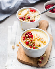 Classic cheesecake in small ceramic jars with fresh cranberries, nuts and honey on light concrete background and wooden board. The most delicious dessert or the perfect healthy breakfast!)