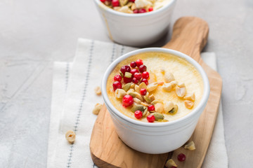 Classic cheesecake in small ceramic jars with fresh cranberries, nuts and honey on light concrete background and wooden board. The most delicious dessert or the perfect healthy breakfast!)