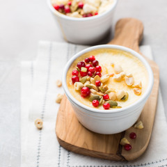 Classic cheesecake in small ceramic jars with fresh cranberries, nuts and honey on light concrete background and wooden board. The most delicious dessert or the perfect healthy breakfast!)