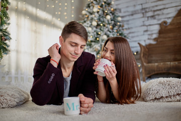 couple holding mugs against  christmas tree in room (1)