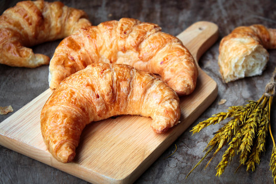 freshly baked croissants on wooden cutting board, top view